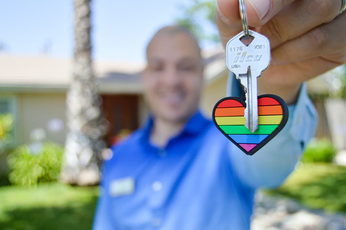 Smiling landlord offering key on rainbow keychain