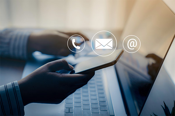 Person on laptop with phone on hand