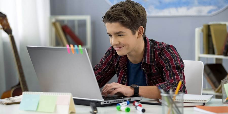 teen boy using laptop at desk