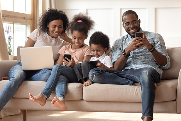 family on couch all using digital devices