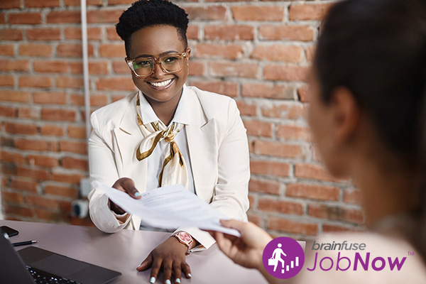 happy woman in business suit handing her resume to interviewer