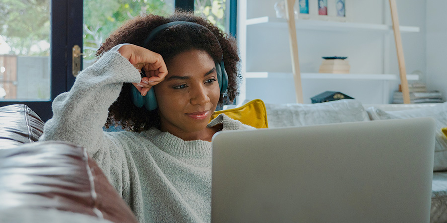 woman watching laptop and wearing headphones at home
