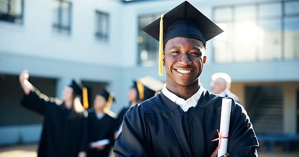 young man in cap and gown smiling ouside